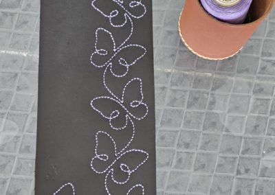 broderie d'une frise "papillons" en 3 mm avec un fil ciré de 0.8mm mauve sur une future petite pochette noire en cuir épais
